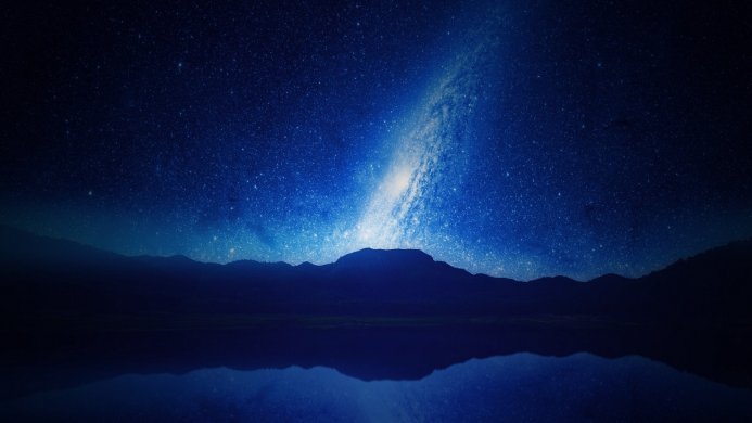 Milky Way over mountains reflected in a lake at night