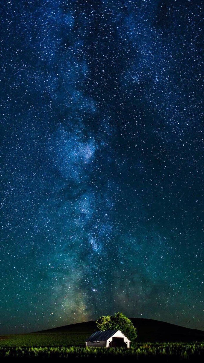 Milky Way and a barn at night in a field