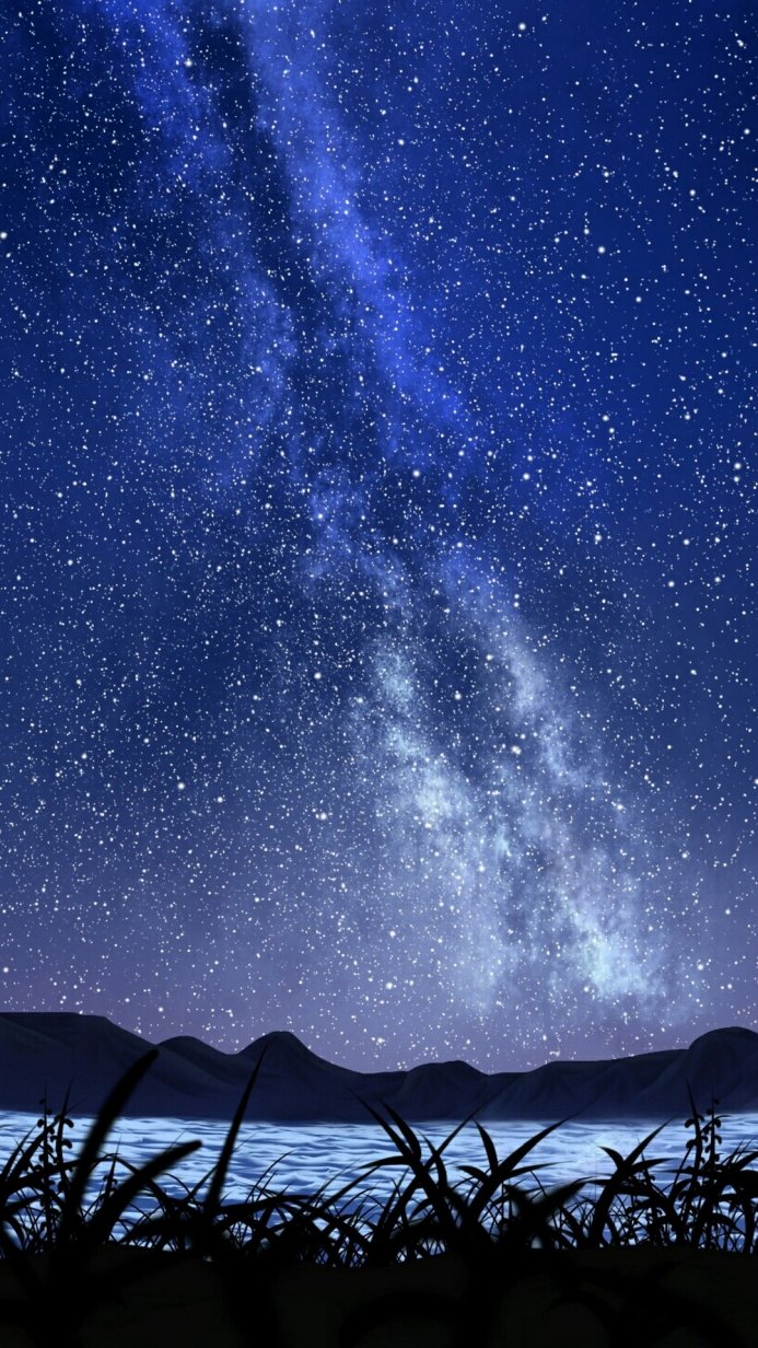 A view of milky way above the lake, with mountains and grass in the foreground