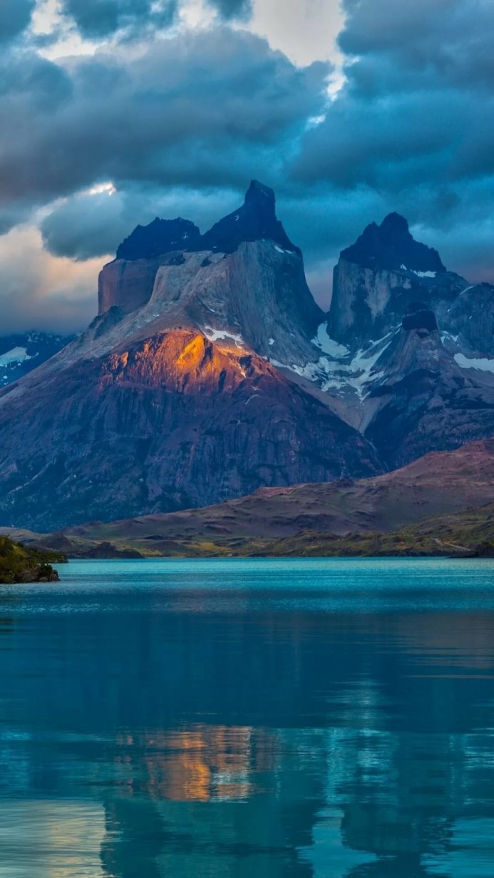 Mountain range reflecting in a still lake under a cloudy sky