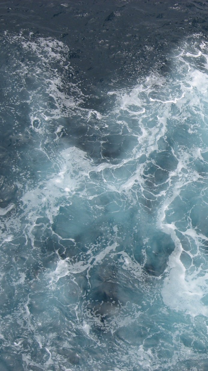 Overhead shot of ocean water with white foam and waves, showcasing texture and movement