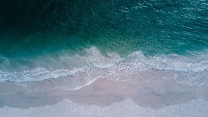 Aerial view of ocean waves meeting a sandy beach