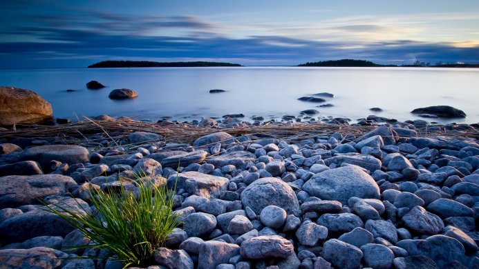 Rocks on a shoreline with calm water and islands in the distance
