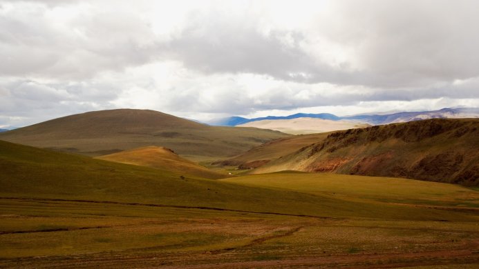 Rolling hills and mountains under a cloudy sky