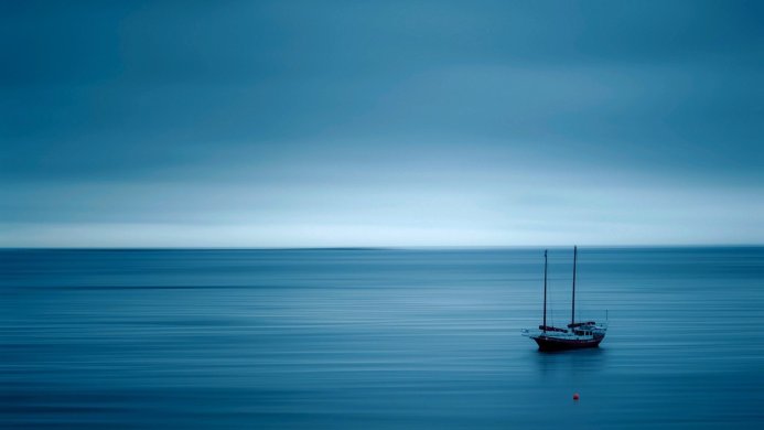 Sailboat on calm blue sea under a serene sky