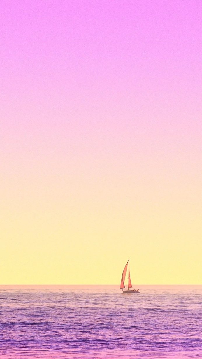A sailboat on the ocean at sunset with pink and yellow sky