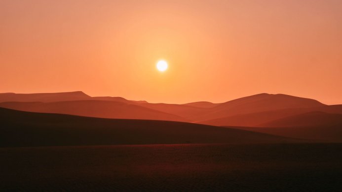 Sand dunes with the sun in the sky, orange landscape