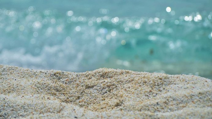 Close-up of sand with bokeh of the turquoise sea in the background