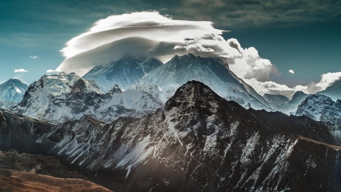 A scenic view of snow-capped mountains under a cloudy sky