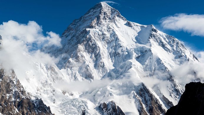 Snow-covered mountain peak against a blue sky with clouds