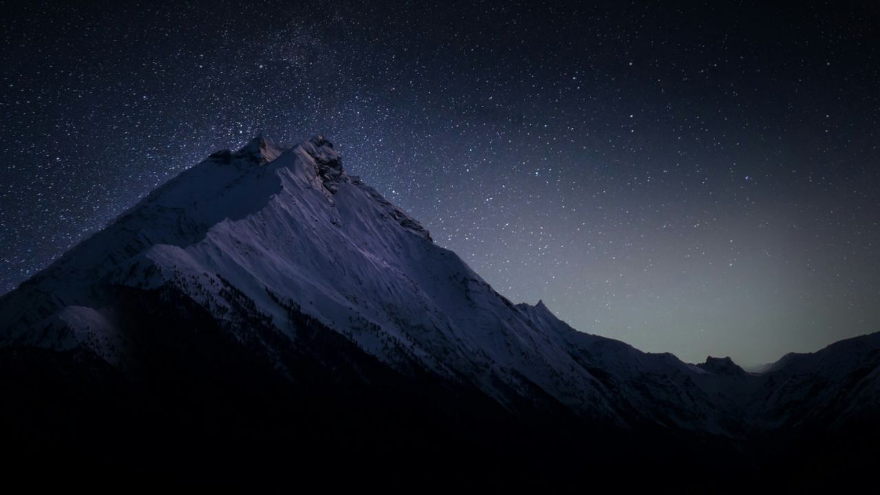 Snowy mountains under a starry night sky