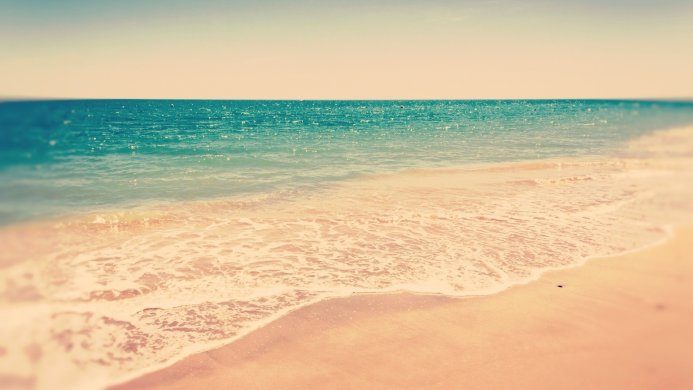 A tranquil beach scene with turquoise water gently lapping against the sandy shore