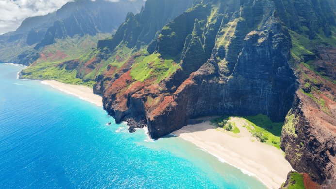 Aerial view of a tropical coastline with mountains, beach, and turquoise ocean