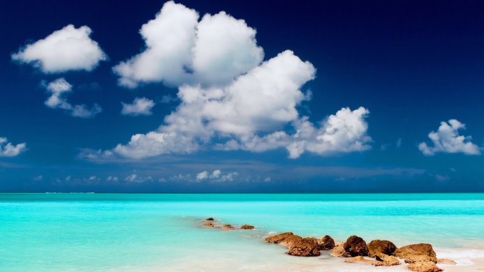 Beautiful turquoise sea with rocks and white clouds in a bright blue sky