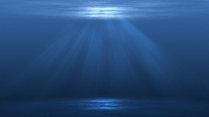 Sunlight streaming through blue water, creating rays and reflections on the bottom