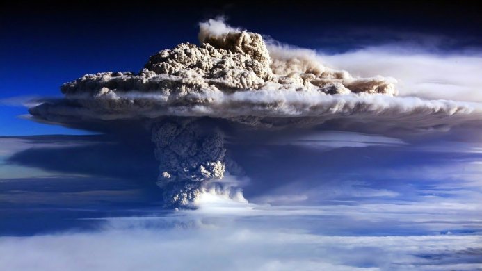 A massive ash cloud rising from a volcanic eruption, seen from above the cloud layer