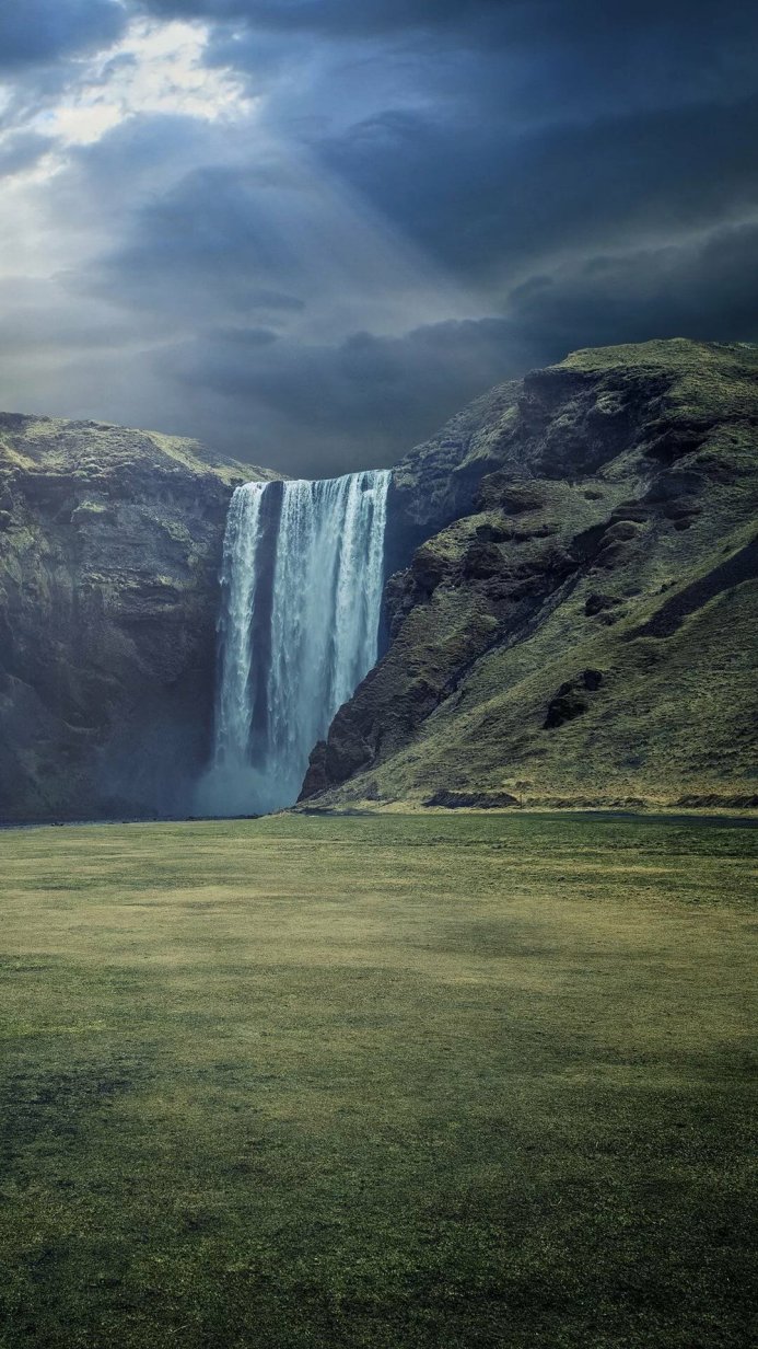 Majestic waterfall cascading down a rocky cliff under a dramatic sky