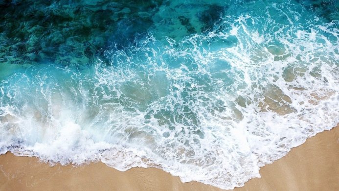 Waves crashing on a sandy beach, aerial view