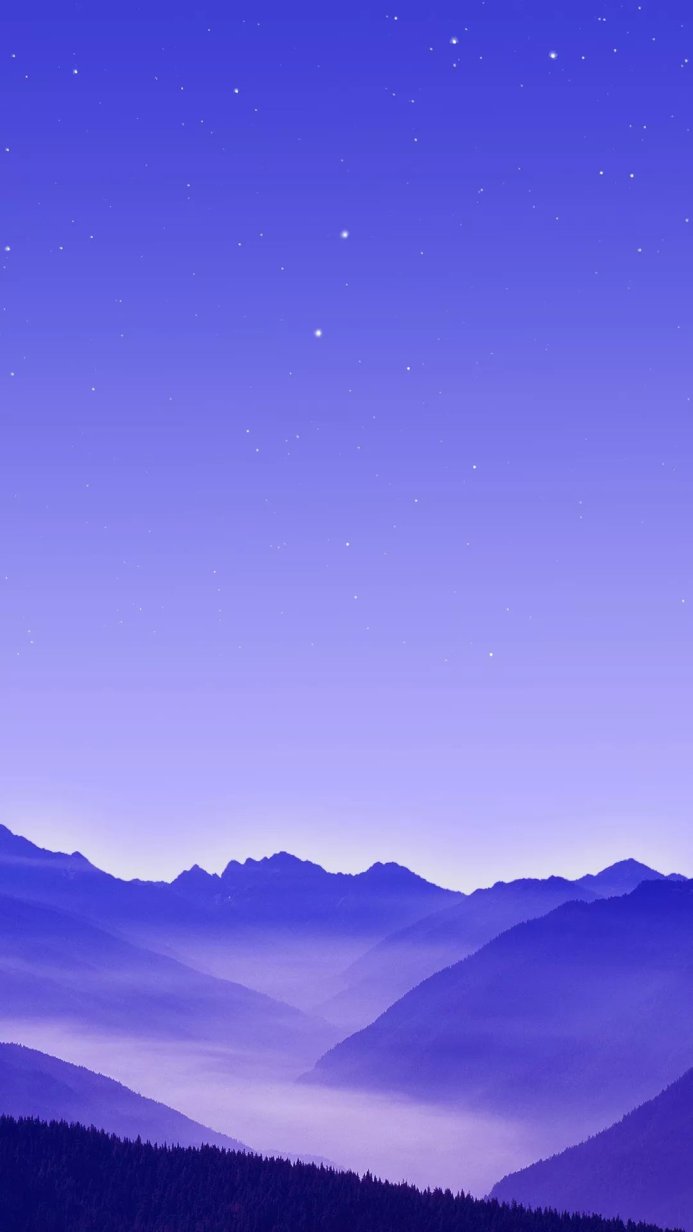 A scenic view of blue mountains under a starlit sky