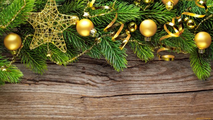 Christmas ornaments, gold star and ribbon, on pine branches over a wooden background
