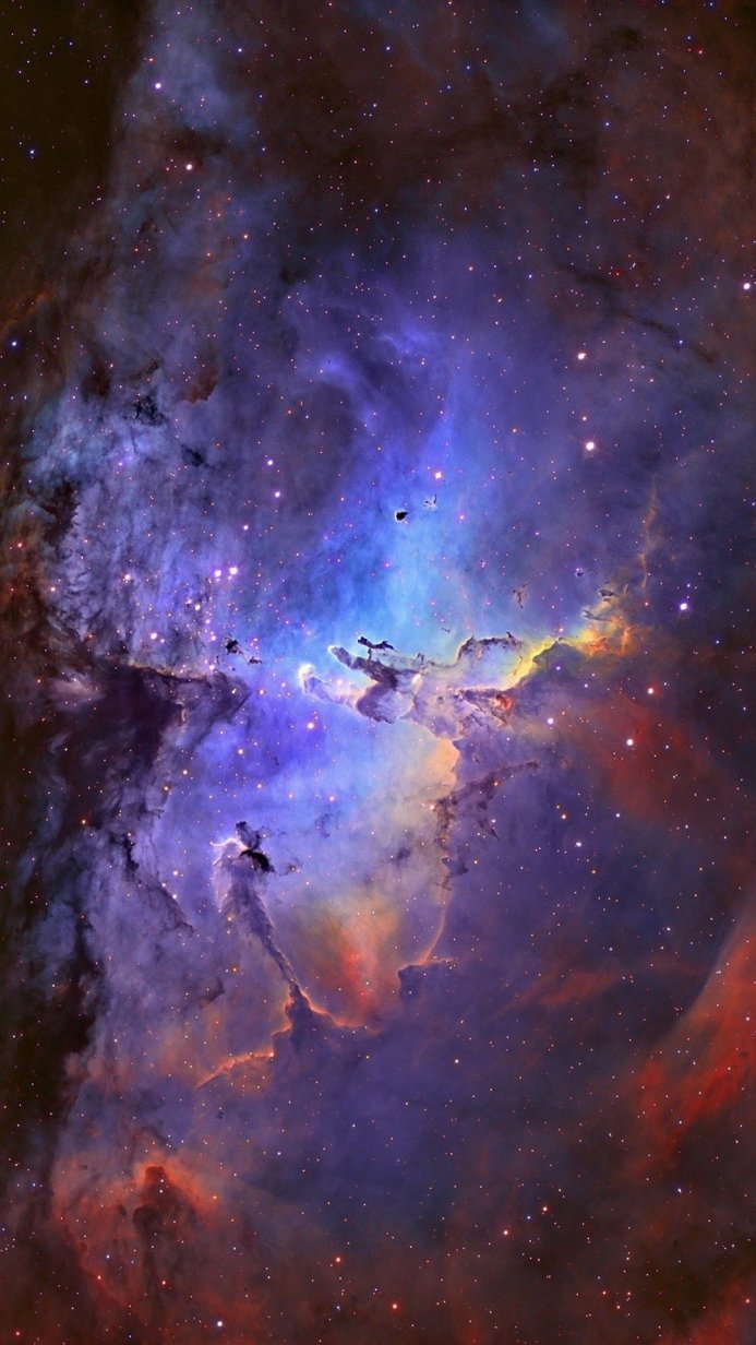 A vibrant nebula with blue, purple, red, and gold hues, filled with stars