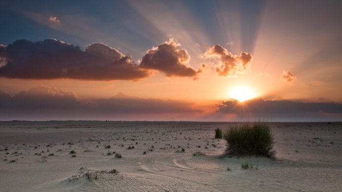 Sunset in the desert with clouds and sun rays