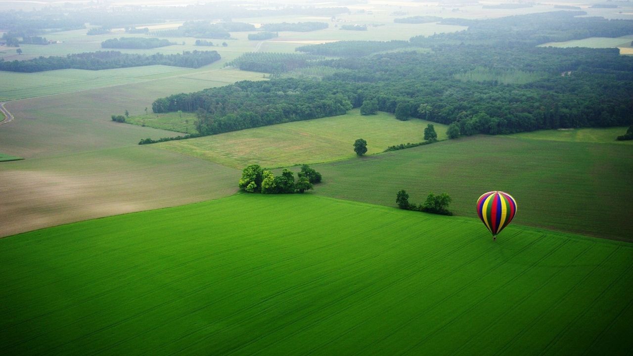 Hot air balloon over green fields