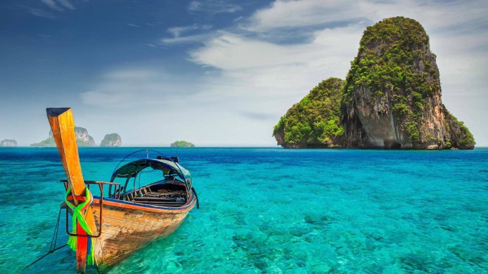 Longtail boat in turquoise water with islands in the background