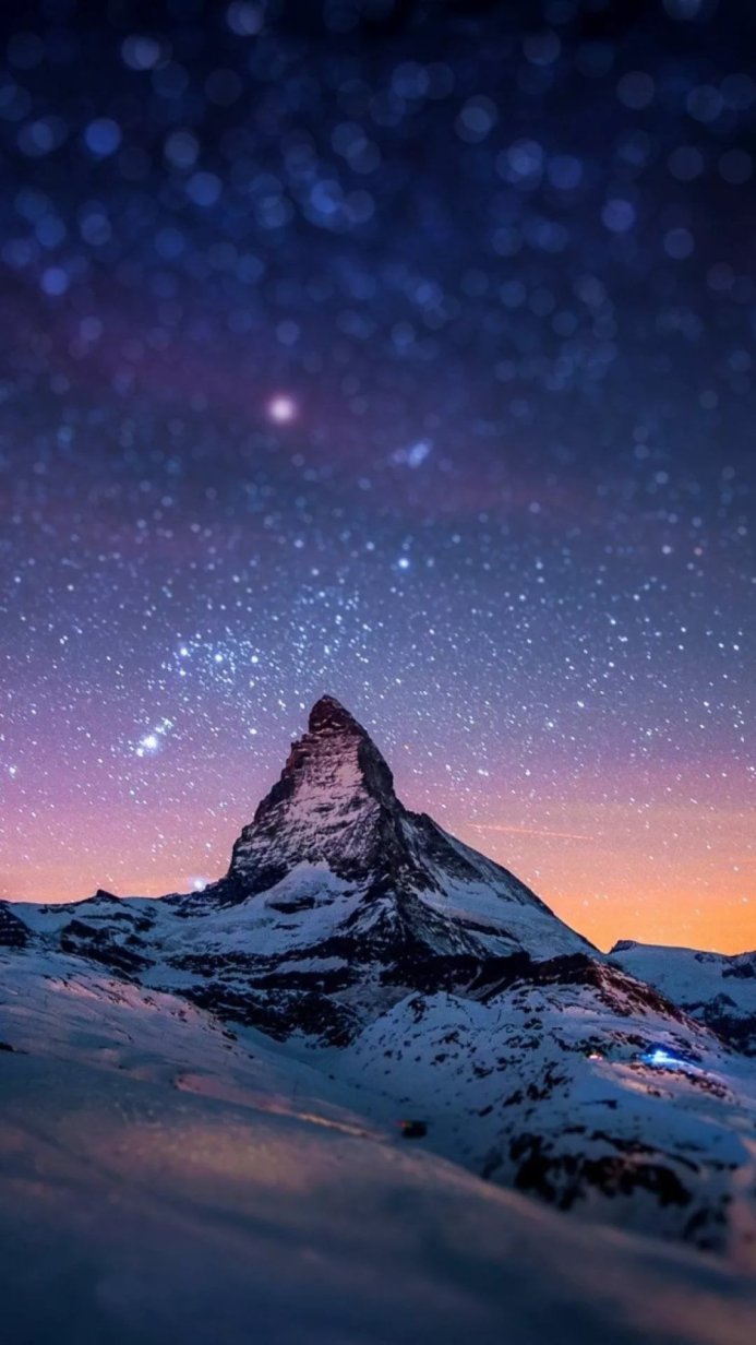 Matterhorn mountain under a starry night sky with snow-capped peaks