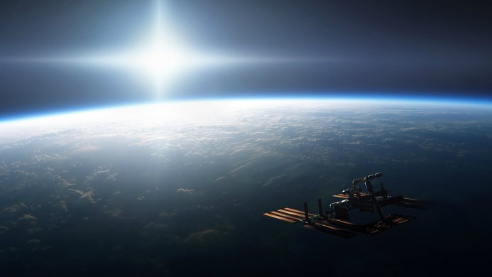 International Space Station orbiting Earth with clouds and a bright sun in the distance