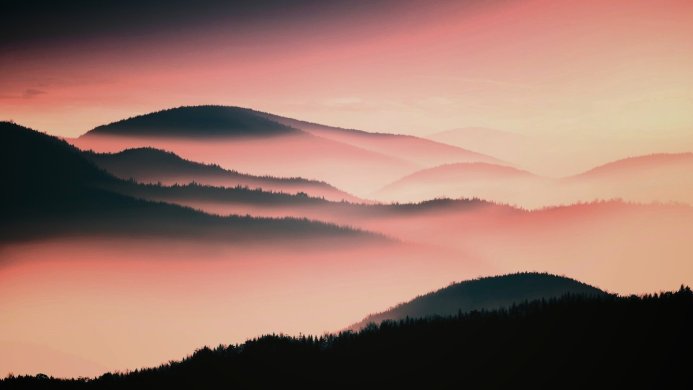 Misty mountains layered in pink and dark tones