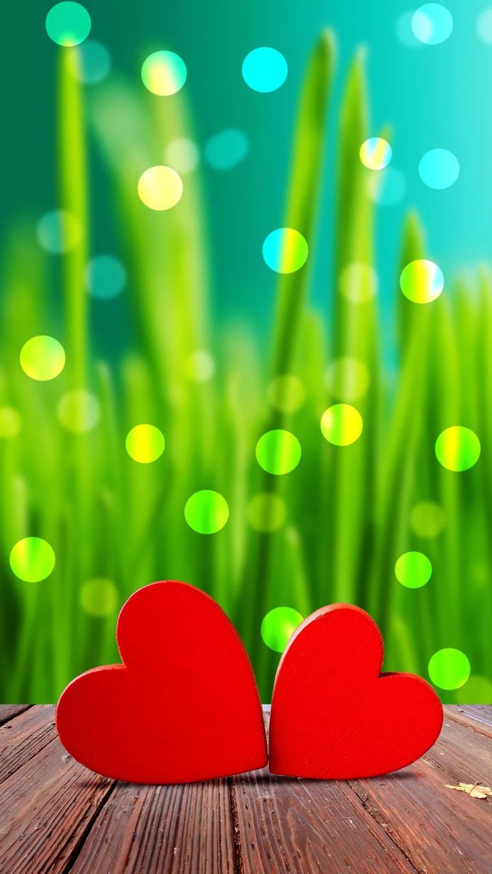 Two red hearts on a wooden table with a green bokeh background