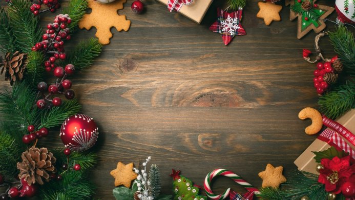 Christmas decoration with pine branches, cookies, a red ornament and gift boxes on wooden background