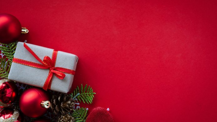 Gift box, red christmas balls, pine cones on red background