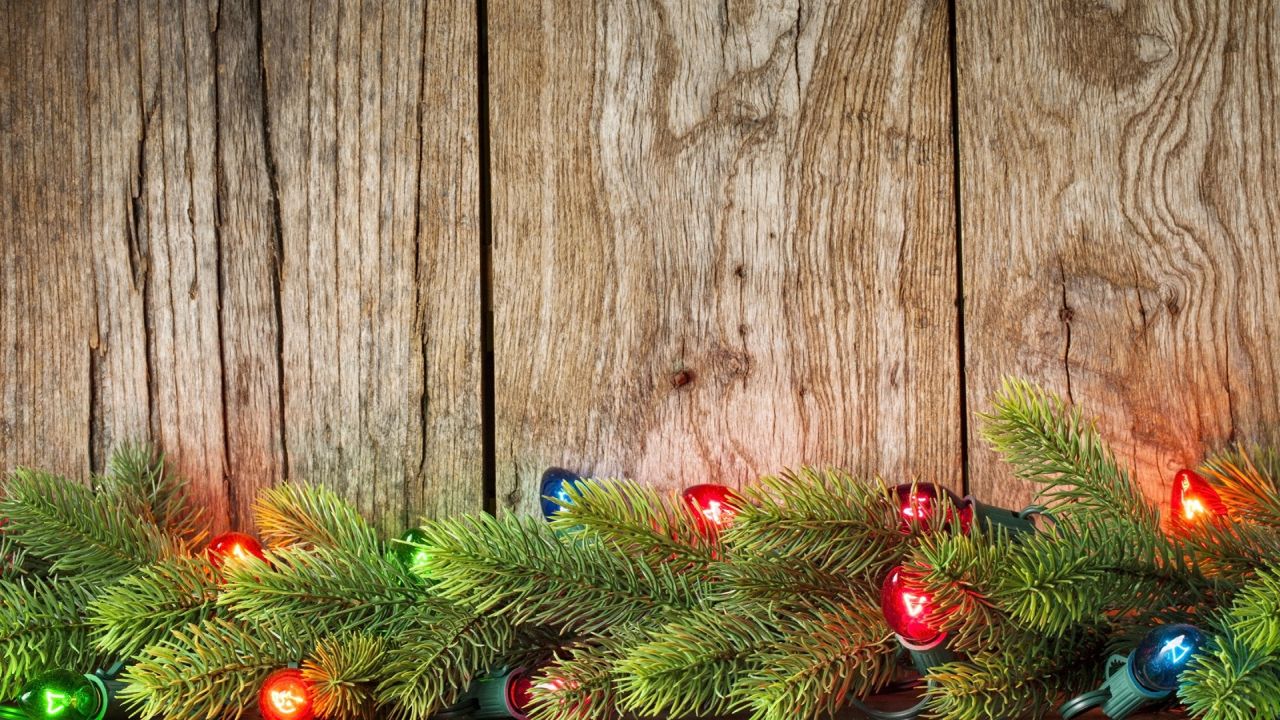Christmas lights on fir branches and wooden background