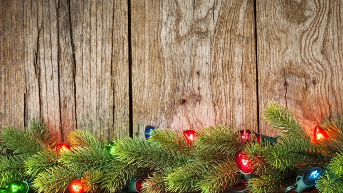 Christmas lights and pine branches on a wooden background