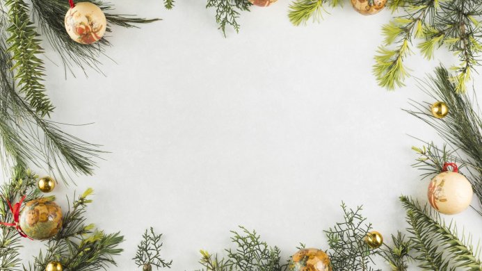 Christmas ornaments and pine branches frame a white background