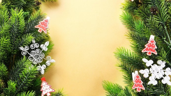 Christmas decorations with pine branches, snowflakes and small christmas trees on a beige background