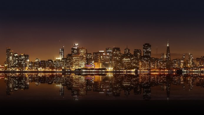 City skyline at night reflecting in water