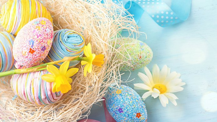 Colorful Easter eggs with flowers and ribbons on a light blue surface