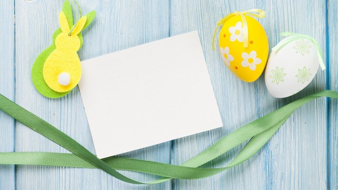 Easter eggs, bunny, and a blank card on a blue wooden background