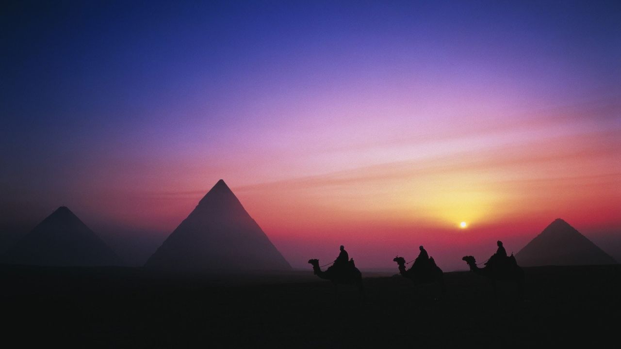 Pyramids and camels at sunset