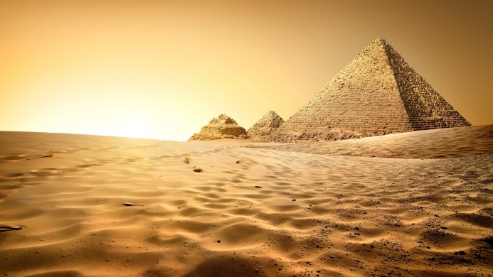 Three pyramids in the desert under a yellow sky