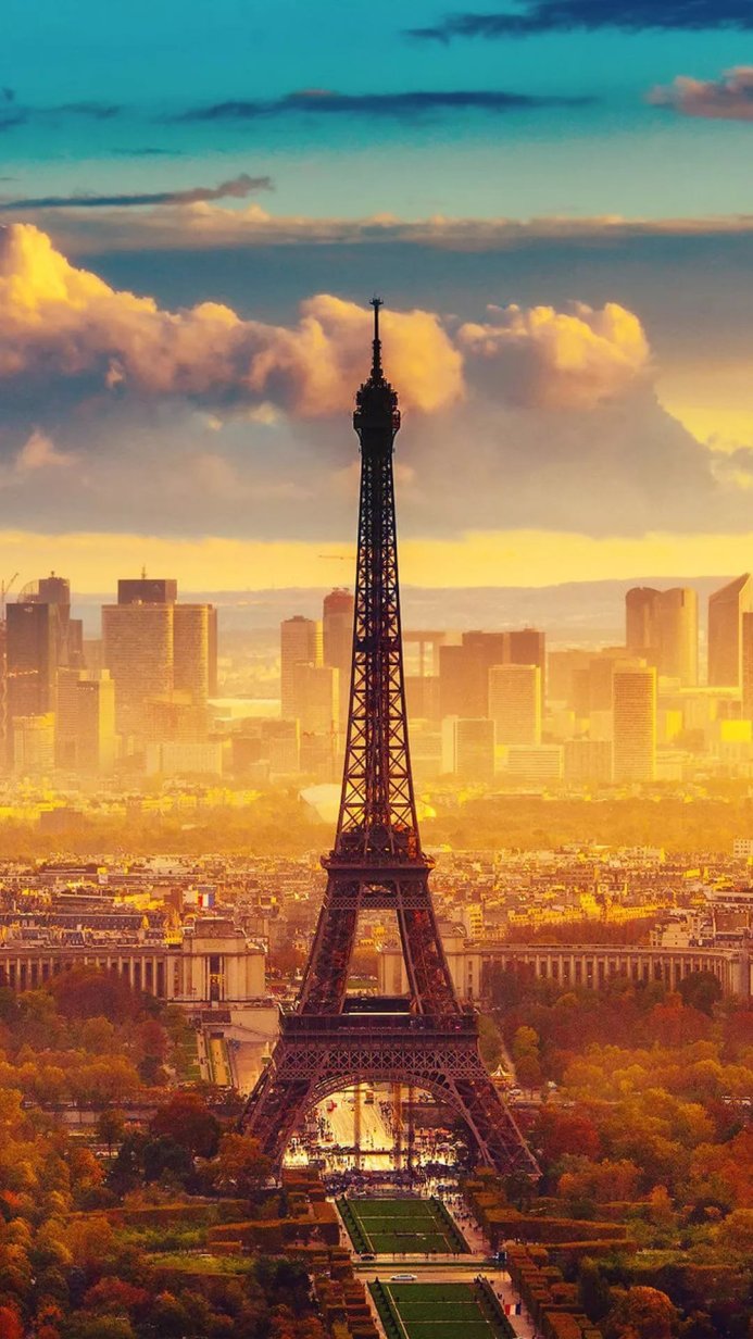 The Eiffel Tower with a cityscape in the background under a cloudy sky during golden hour
