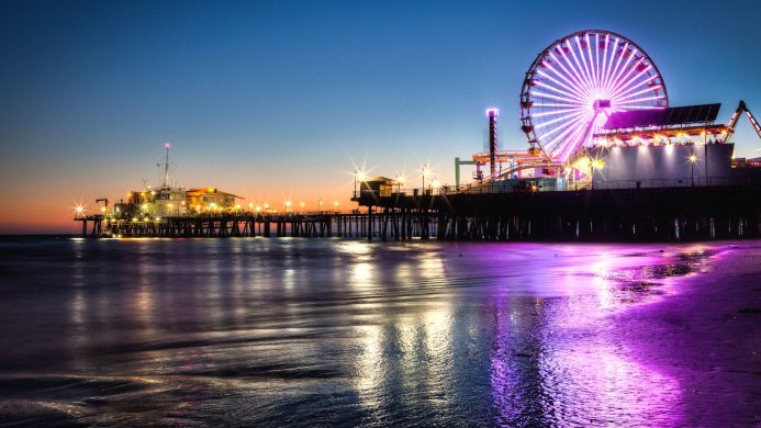 Ferris wheel and pier at night, with reflections in the water