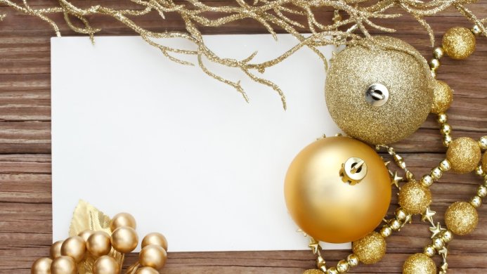 Gold Christmas ornaments with blank card on a wooden background