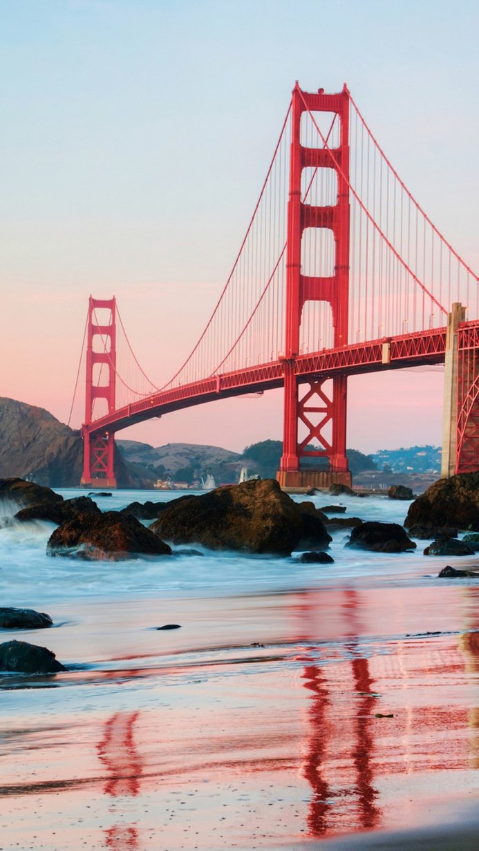 Golden Gate Bridge at sunset, waves crashing on the shore