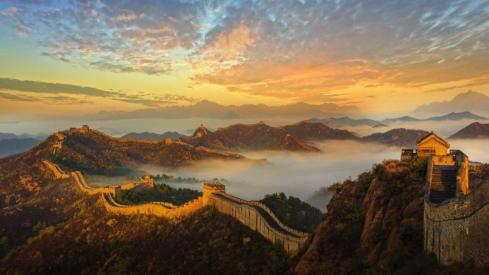 The Great Wall of China winding through mountains at sunrise