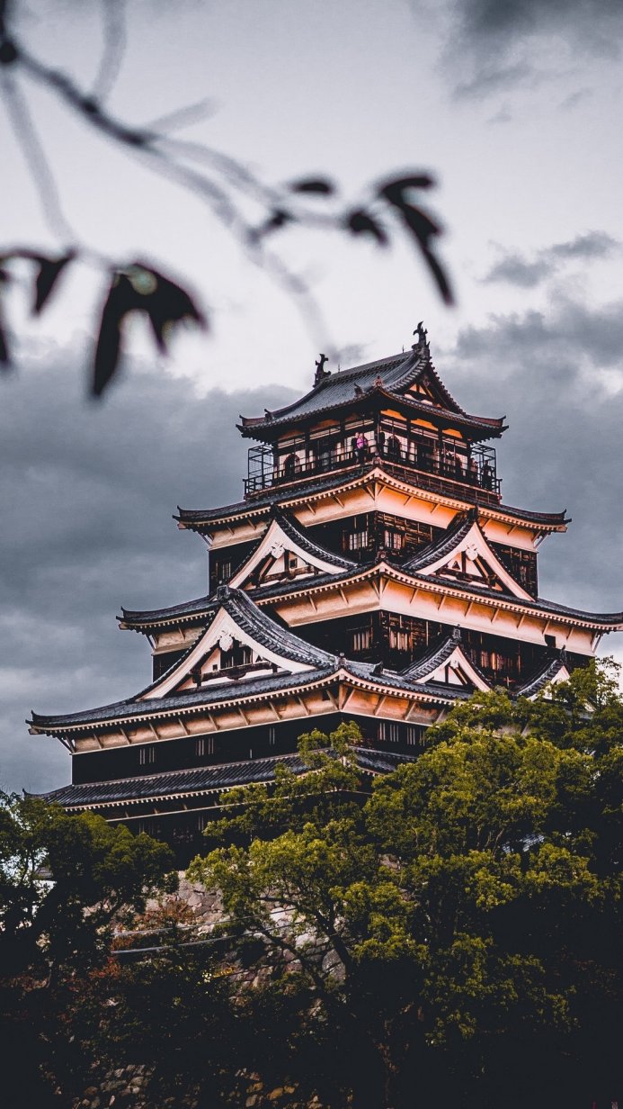A traditional Japanese castle with dark tones and a cloudy sky