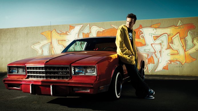 Jesse Pinkman leaning on a red 1982 Chevrolet Monte Carlo with graffiti background